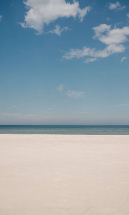 Plage de sable blanc au bord de la mer, horizon paisible représentant l’apaisement et la liberté intérieure.