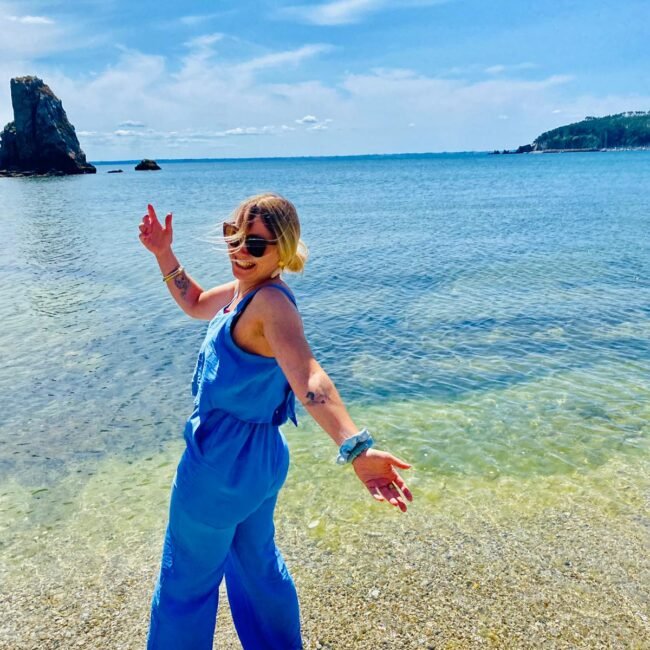 Femme souriante en combinaison bleue dans la mer, symbole de confiance retrouvée