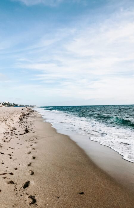 Plage avec empreintes de pas dans le sable au bord de la mer, illustrant le chemin personnel et l’avancée étape par étape.