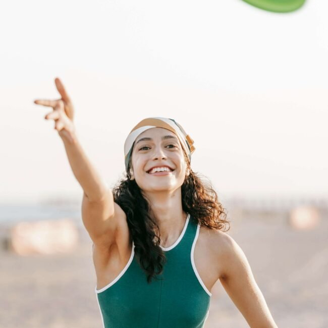 Jeune femme souriante levant les bras vers le ciel, symbole de joie, de liberté et d’épanouissement personnel.