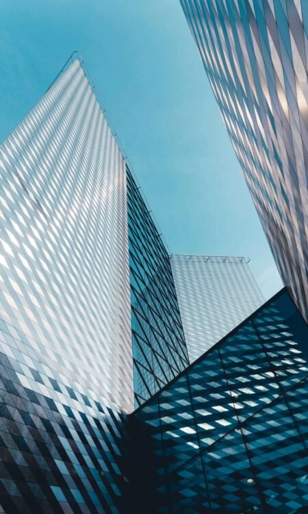 Vue en contre-plongée de gratte-ciel modernes sous un ciel bleu, représentant la vision stratégique et l’innovation en entreprise.